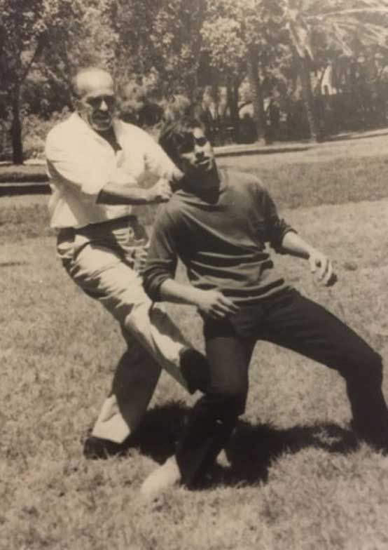 Imi Lichtenfeld, l'ideatore del Metodo Krav Maga, applica una leva per portare a terra l'avversario da dietro, destabilizzando l'appoggio della gamba destra